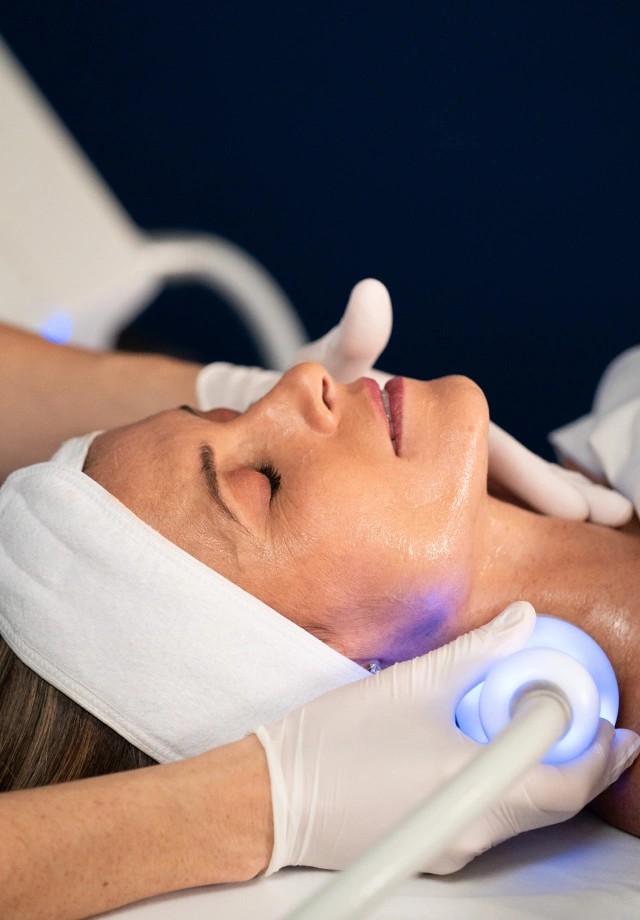 Gloved practitioner guiding a lighted applicator along a client's jawline and neck during a Neveskin skin wellness treatment at Lovejoy Chiro & Med Spa in Allen, TX