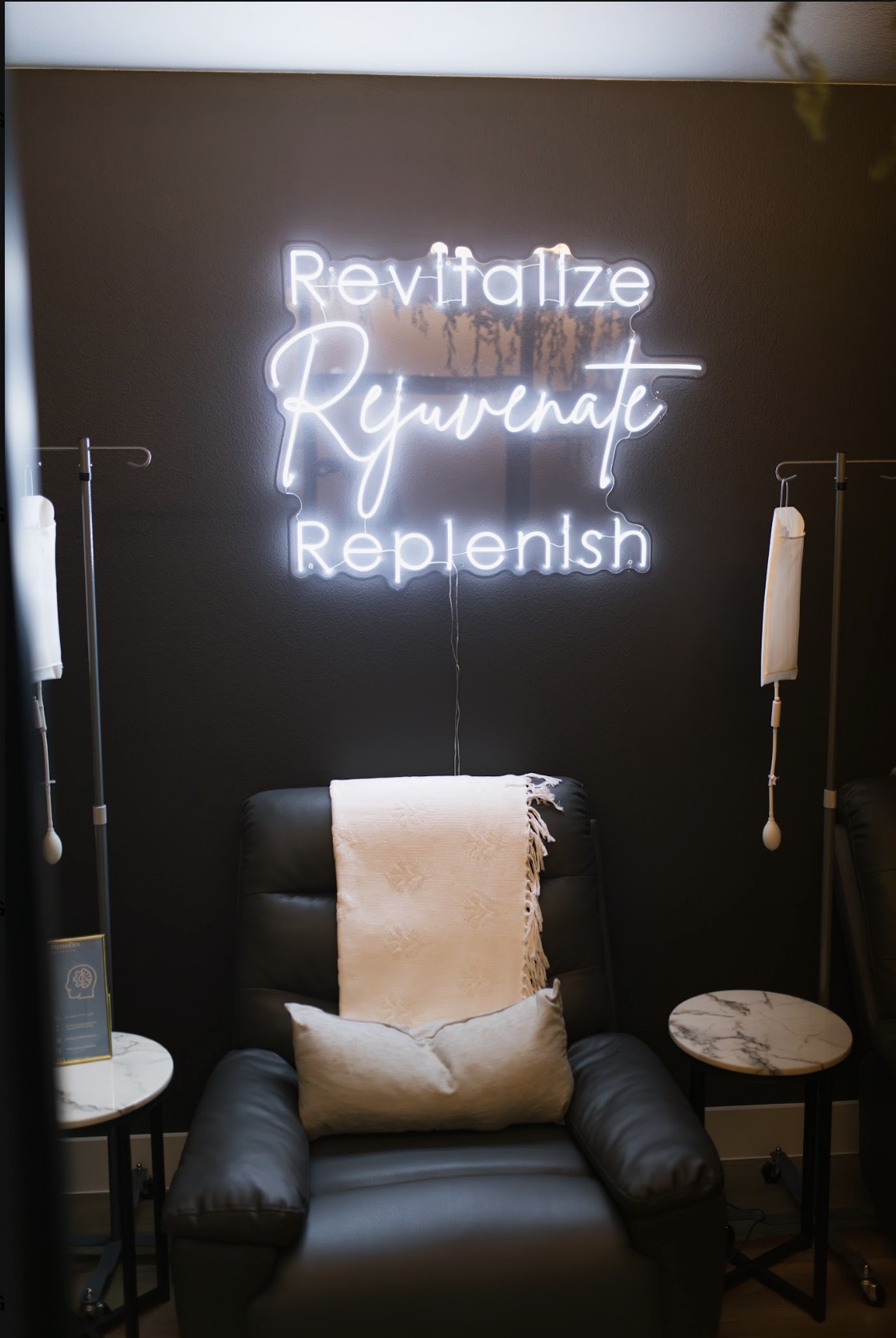 IV therapy lounge at Lovejoy Chiro & Med Spa in Allen, TX with a leather recliner, IV poles, and a Revitalize Rejuvenate Replenish neon sign